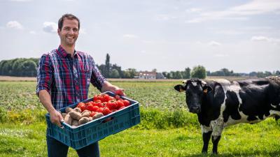 man op veld met bak groenten